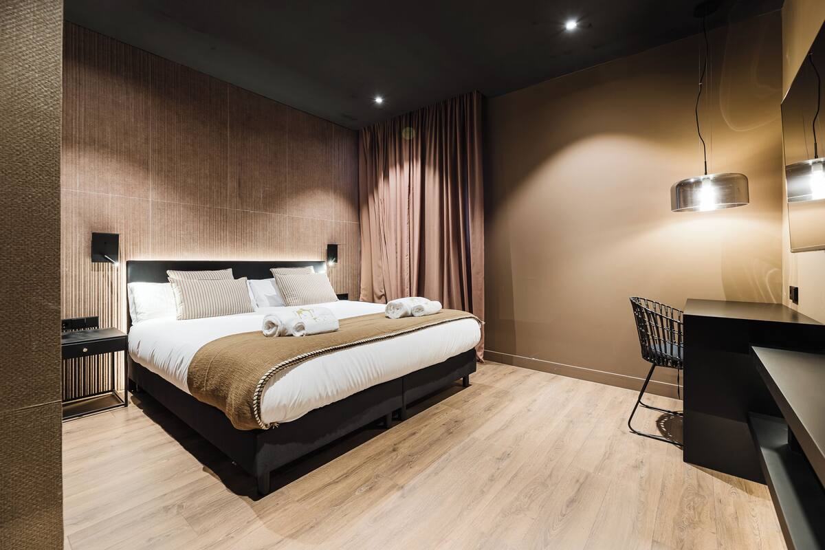 A modern hotel room with a large bed, a desk, and a chair.