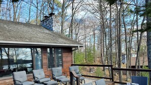 A wooden deck with outdoor seating and a table set for dining, surrounded by trees. - Boulder Lakefront and Bike Trail Access (Boulder Junction)