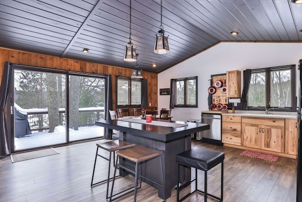 A modern kitchen with a central island, wooden cabinets, and large windows.