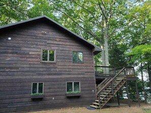 A wooden cabin with a staircase leading to a deck, surrounded by trees. - Boulder Lakefront and Bike Trail Access (Boulder Junction)