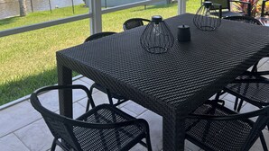 A covered patio with a table and chairs, overlooking a body of water and houses. - Salty Waterways Escape with a dock. Family friendly, boat rental available  (Palm Coast)
