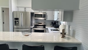 A modern kitchen with stainless steel appliances, a marble countertop, and black chairs. - Salty Waterways Escape with a dock. Family friendly, boat rental available  (Palm Coast)