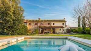 Una casa de piedra de dos pisos con una piscina y un flotador inflable blanco grande.