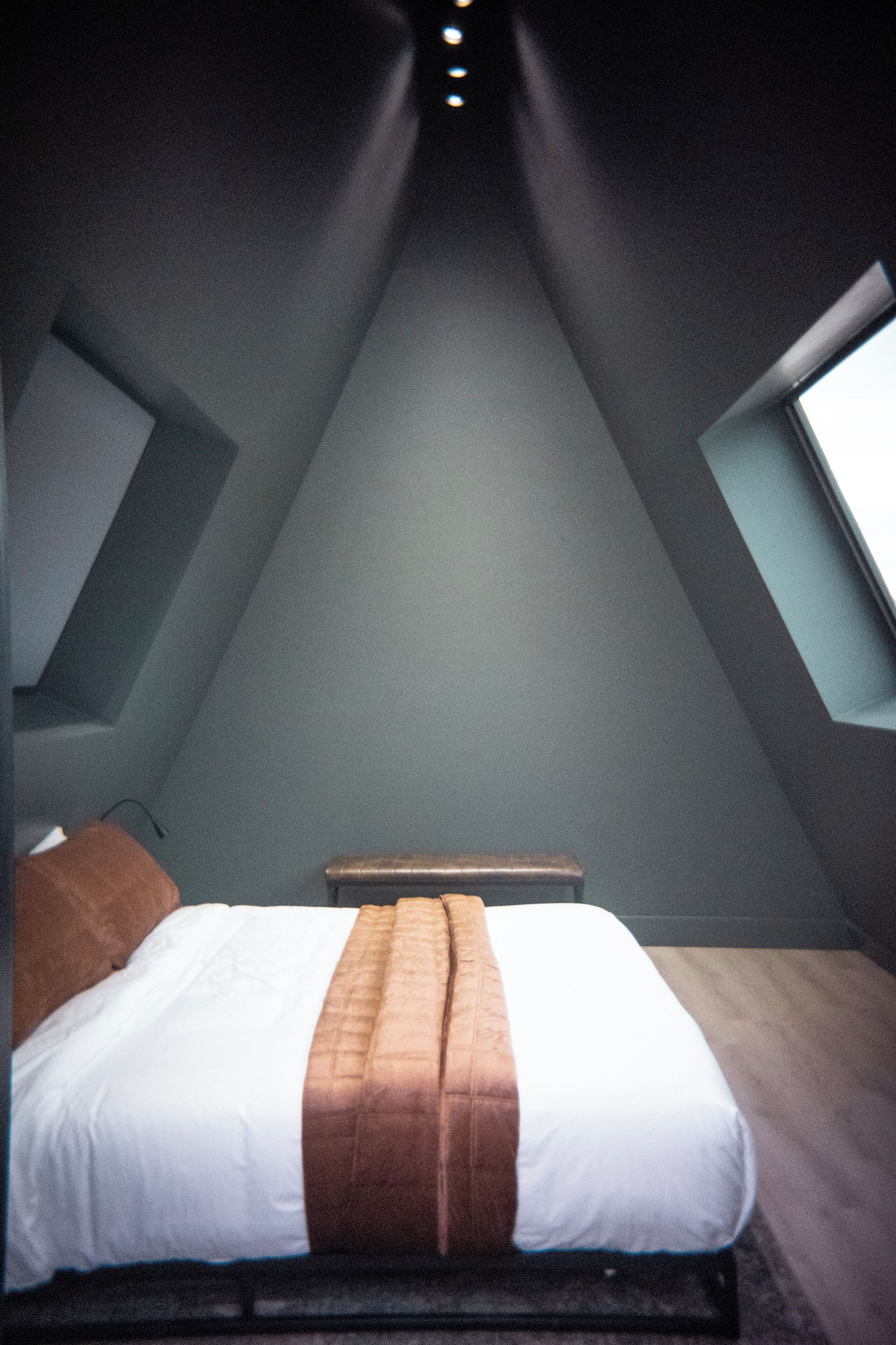 A bedroom with a bed, a nightstand, and a window.
