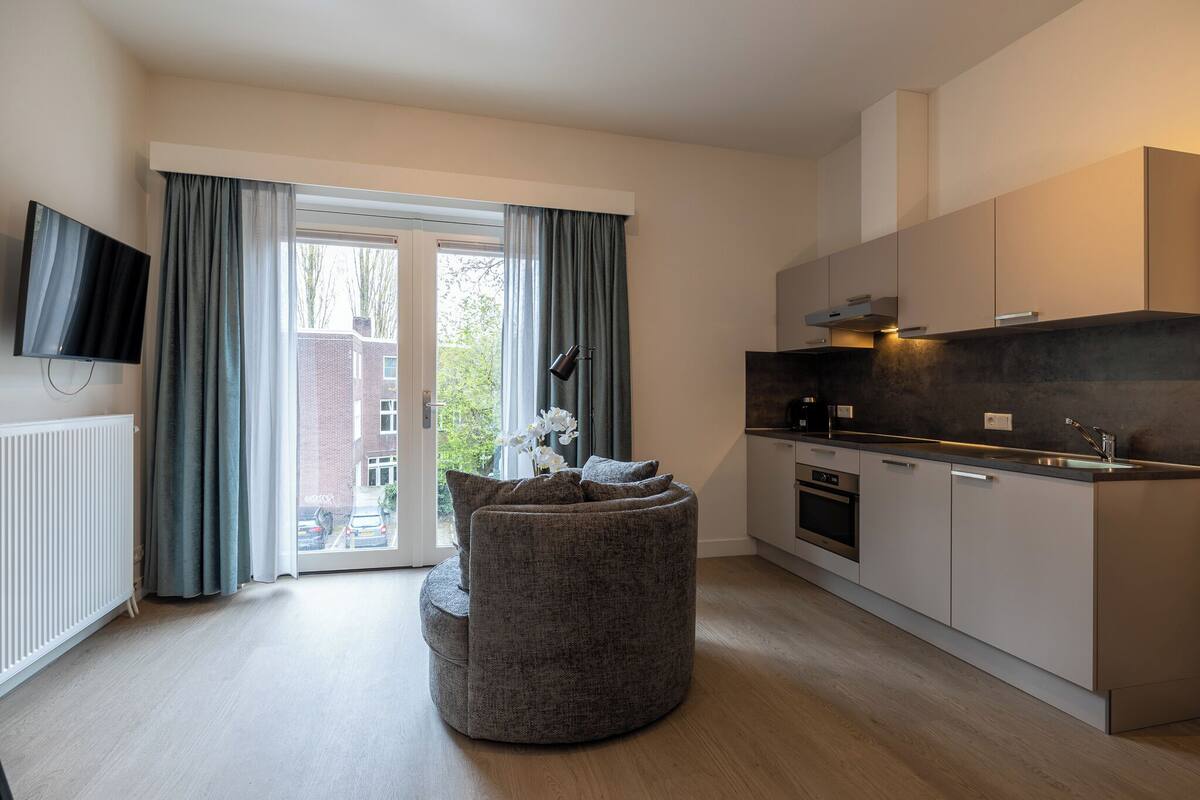 Een moderne keuken met een inbouwoven en een groot raam met gordijnen.