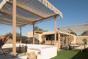 Eine Terrassensitzgruppe im Freien mit einer Pergola, einer Lounge-Ecke und einem Billardtisch.