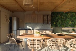 A modern kitchen with a large island, wicker chairs, and a dining table.