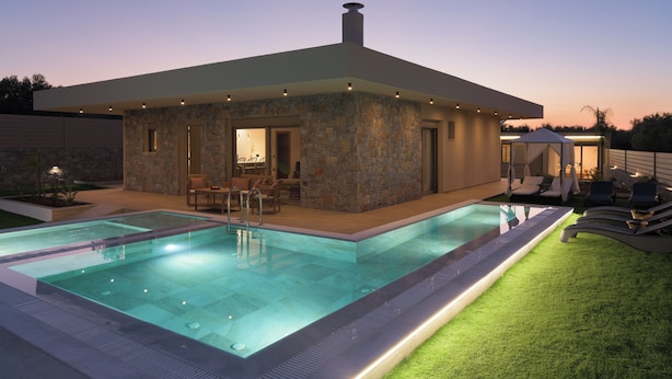 Una casa moderna con piscina, fachada de piedra y zona de estar al aire libre.