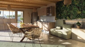 Una cocina amplia con armarios de madera, un comedor con sillas de mimbre y una pared verde con plantas.