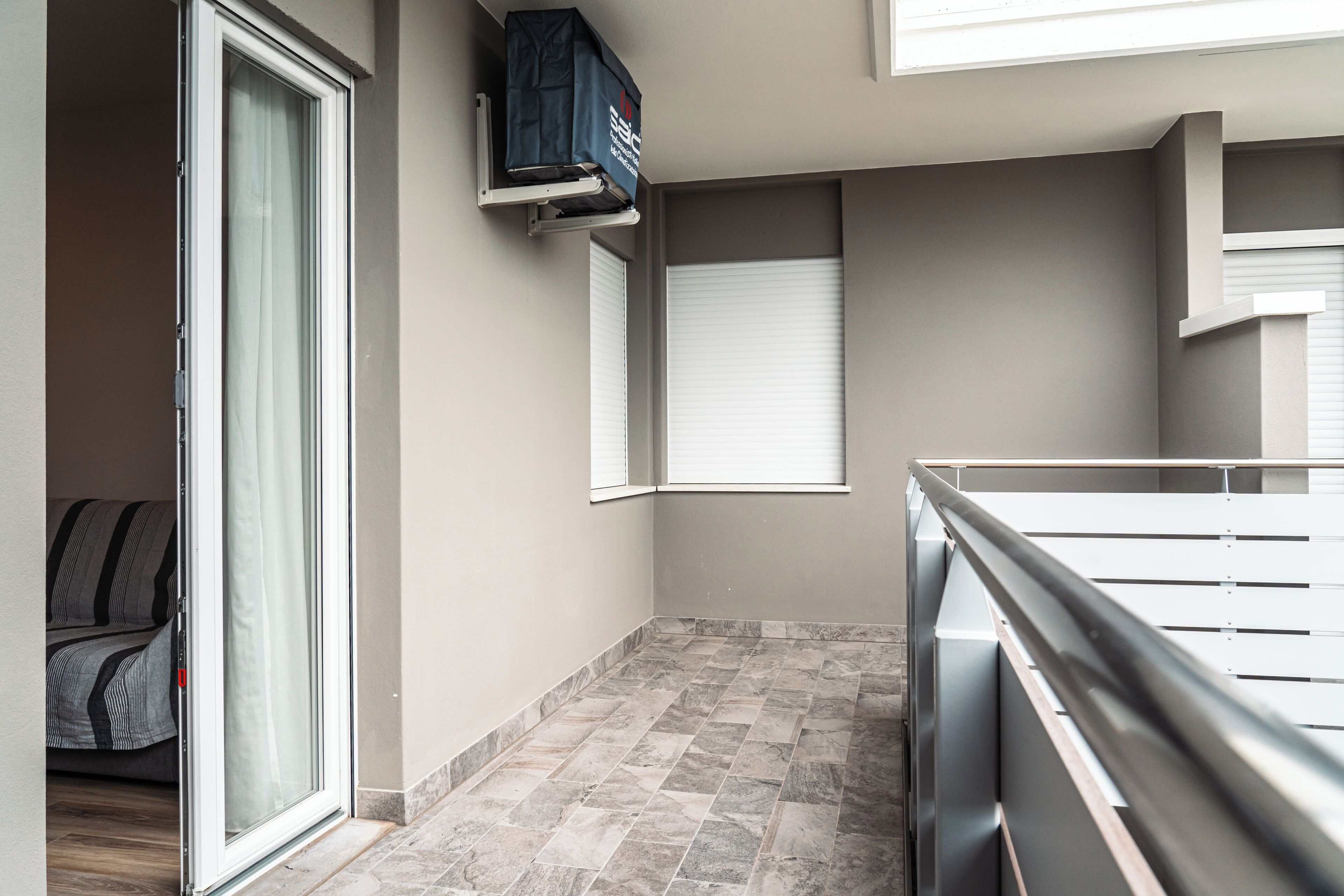 A modern apartment with a sliding glass door, a small balcony, and a tiled floor.