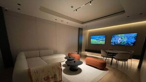 A modern living room with a sofa, ottoman, coffee table, and two flat-screen TVs mounted on the wall. - THE CITY SUITE -  LA RÉSIDENCE PANAMÁ (Panamá)