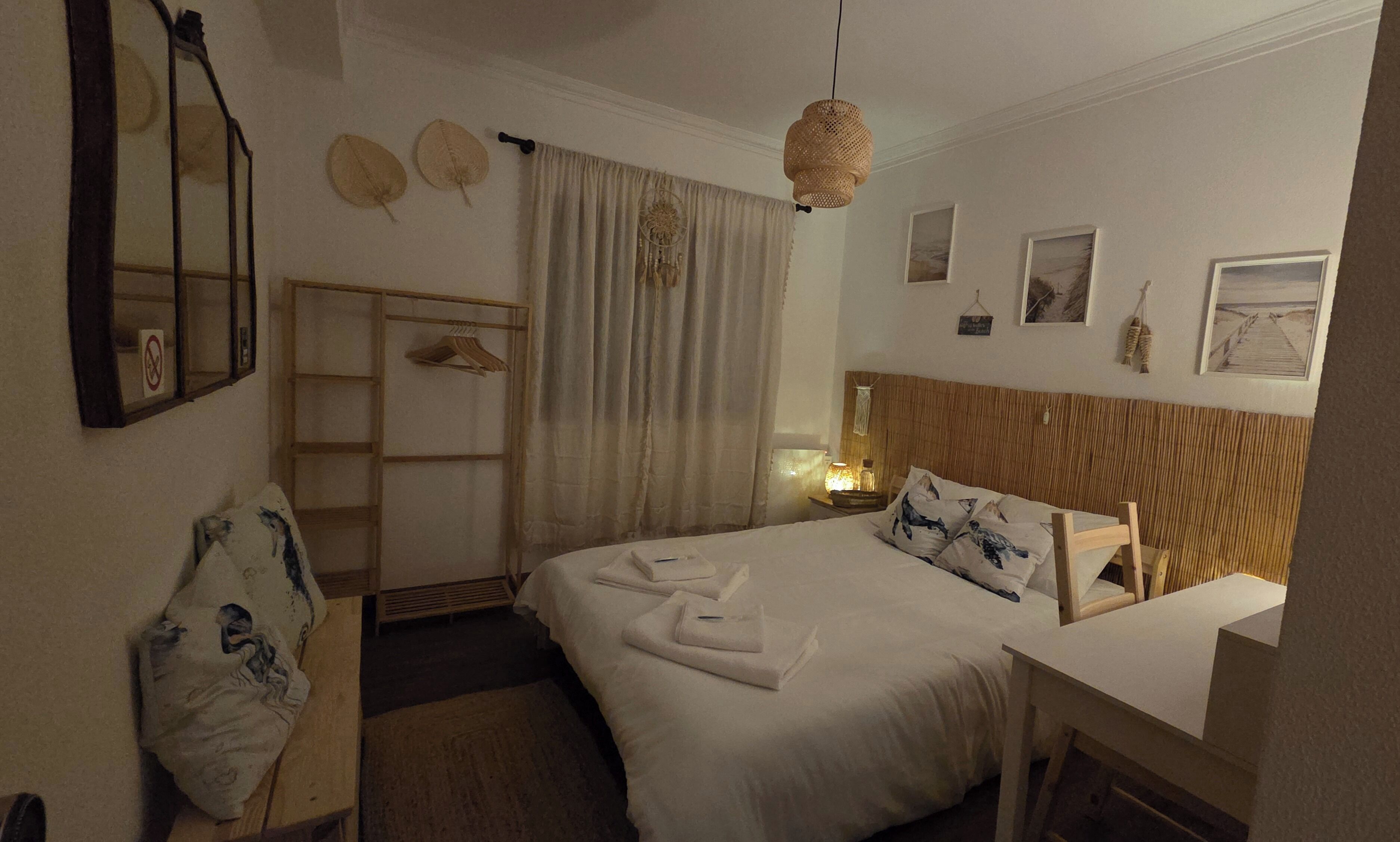 Une chambre d’hôtel avec un lit, un bureau, une armoire et un miroir.