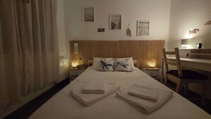 A neatly made bed with two folded towels, a wooden headboard, and a bedside table with a lamp. - Guest House da Mata (A Ver-o-Mar)