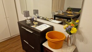 A hotel reception desk with a mirror, a small table with a placemat, a vase with flowers, and a trash bin. - Guest House da Mata (A Ver-o-Mar)