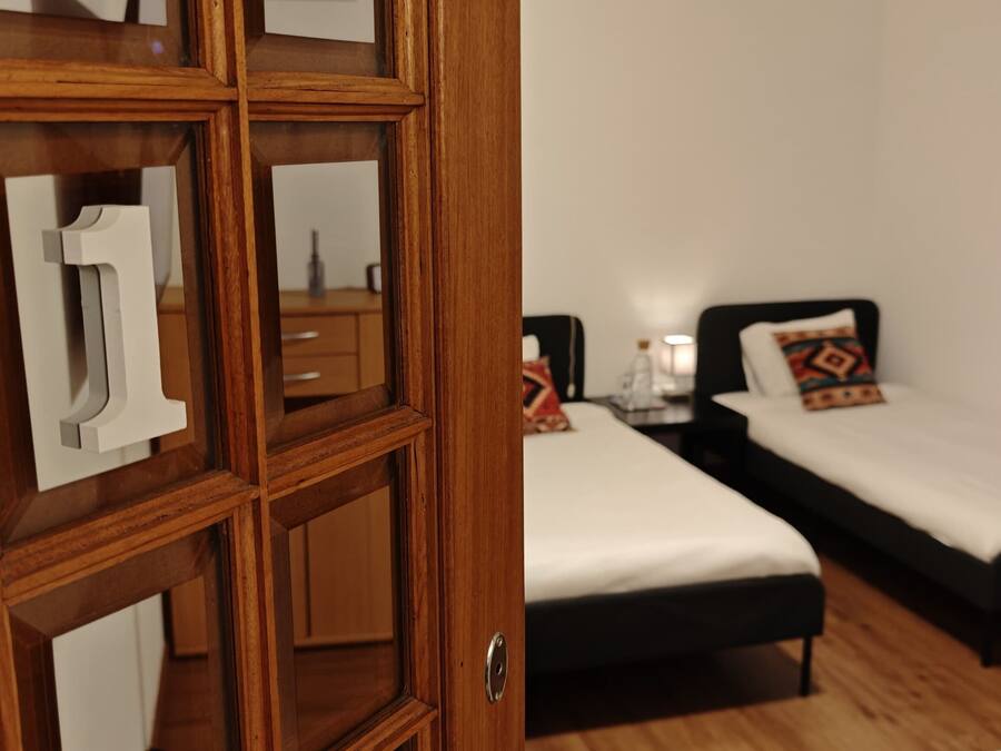 Ein Schlafzimmer mit zwei Einzelbetten, Holzmöbeln und einem Schminkspiegel.