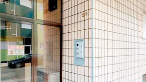 A building facade with a grid of tiles, a door with a sign, and a small window. - Guest House da Mata (A Ver-o-Mar)