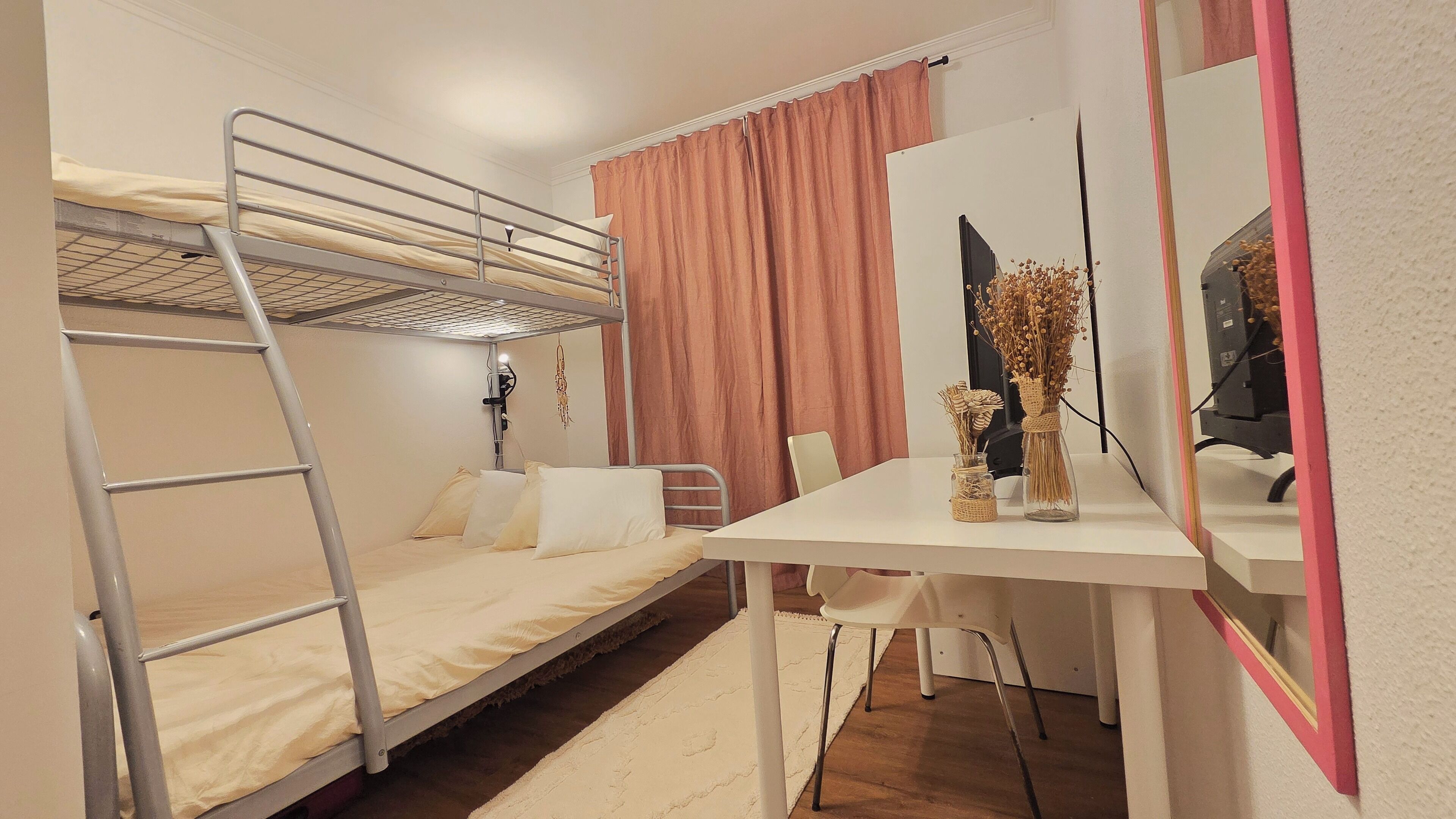 A bunk bed room with a desk, chair, and mirror.