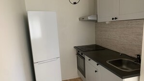 A compact kitchen with a white refrigerator, a stove, and a sink. - Stockholm Apartment - Sleeps 4 & Free Parking (Kista)