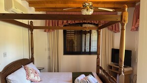 A four-poster bed with a wooden headboard, a green throw blanket, and rolled towels on the side. - Charming Villa in Pano Platres, Cyprus - Your Home Away From Home (Platres)