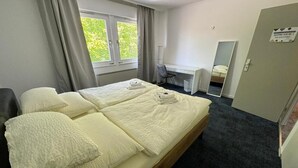 A hotel room with a double bed, a desk, a chair, and a mirror. - HubTime (Algermissen)