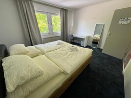 Habitación de hotel con cama doble, escritorio, silla y espejo.