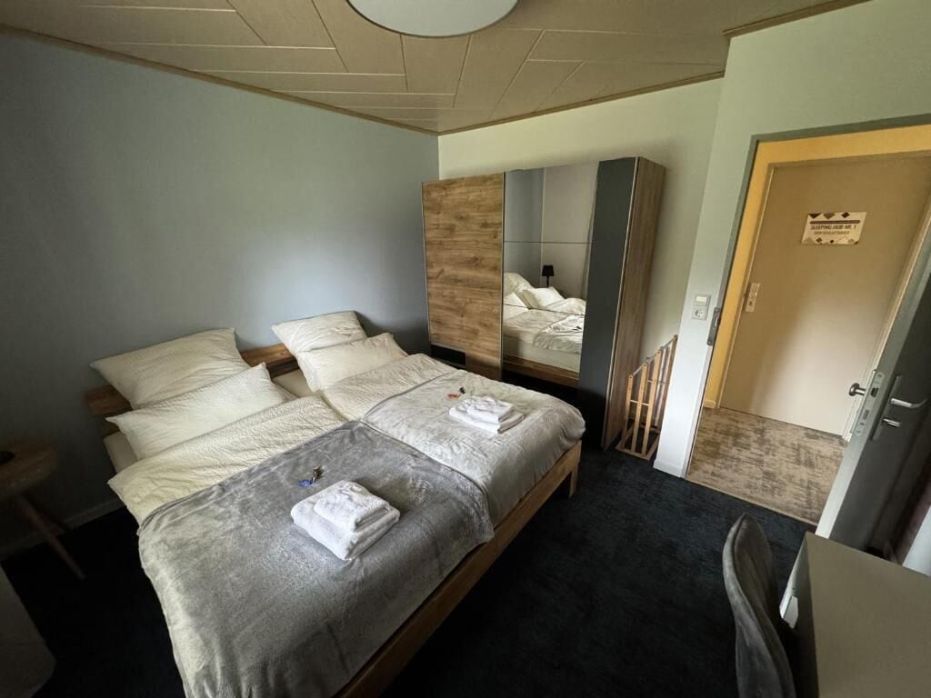 A hotel room with a bed, a mirror, a door, and a small table.