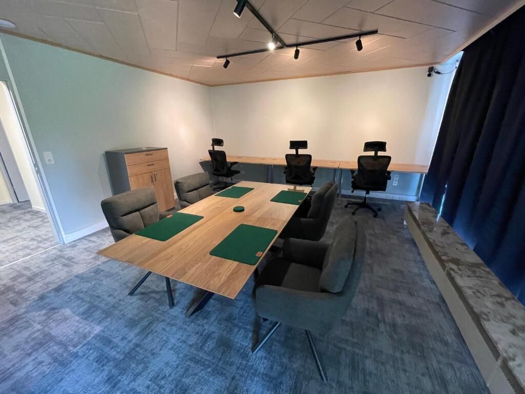 A conference room with a long table, four chairs, and a cabinet.