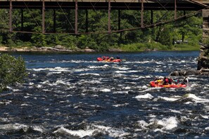 A river with two red inflatable rafts navigating through rapids.