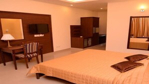 A hotel room with a large bed, a desk with a chair, a television, and a wardrobe. - Surkhab Tourist Resort (Sirsa)