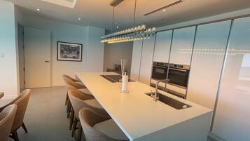 A modern kitchen with a long island, stainless steel appliances, and a pendant light.