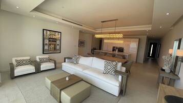 A modern living room with a sofa set, a coffee table, and a dining area in the background.