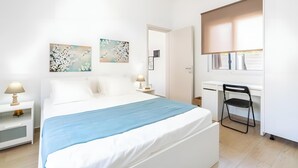 Un dormitorio con cama, mesitas de noche, escritorio y una silla.