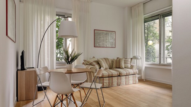 A modern living room with a sofa, chairs, a table, and a lamp. - JOIVY Studio Near Pinacoteca Brera (Milan)