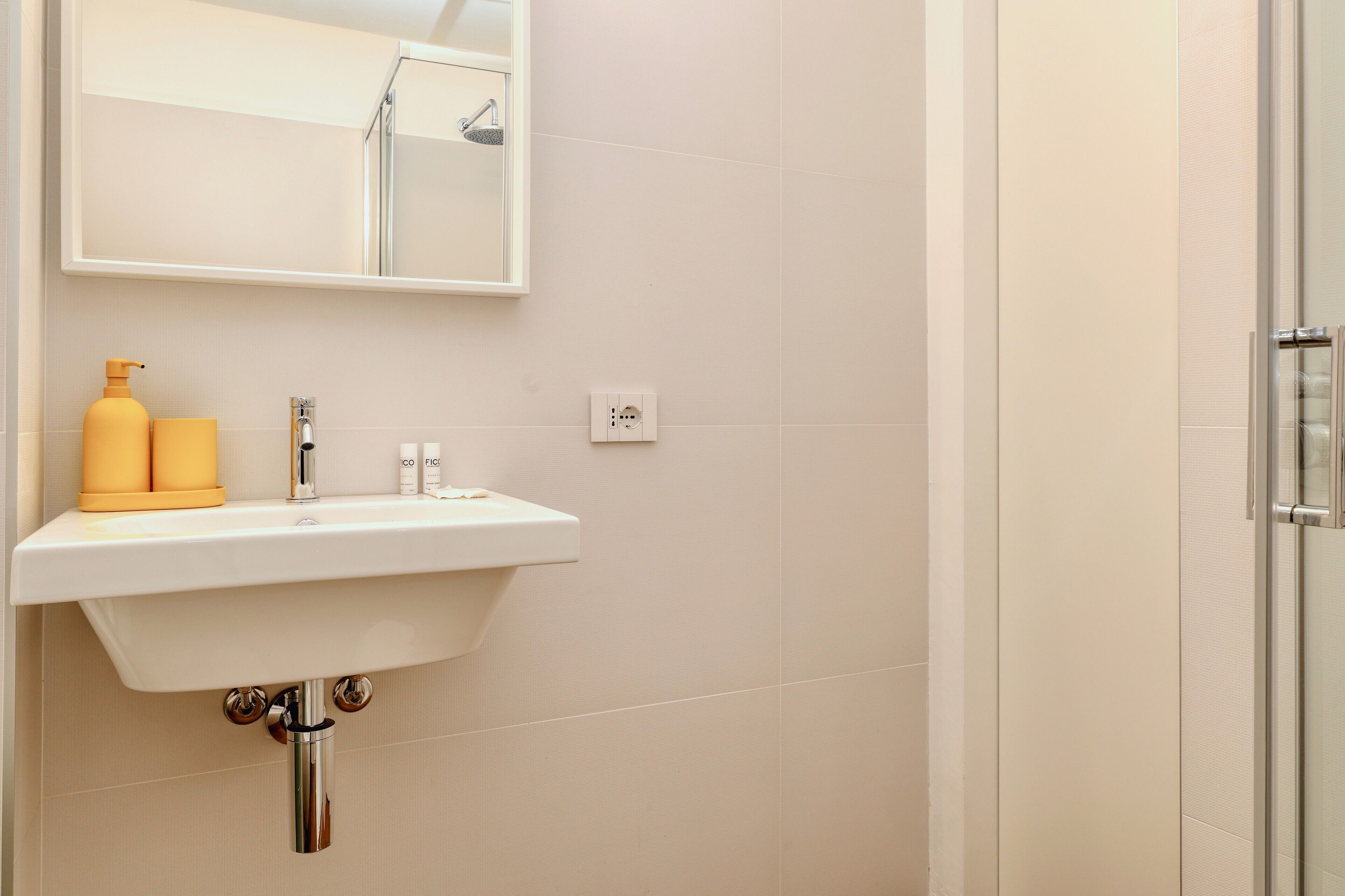 A bathroom with a white sink, a mirror, and a shower.