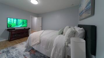 A bedroom with a bed, a television, and a painting on the wall.