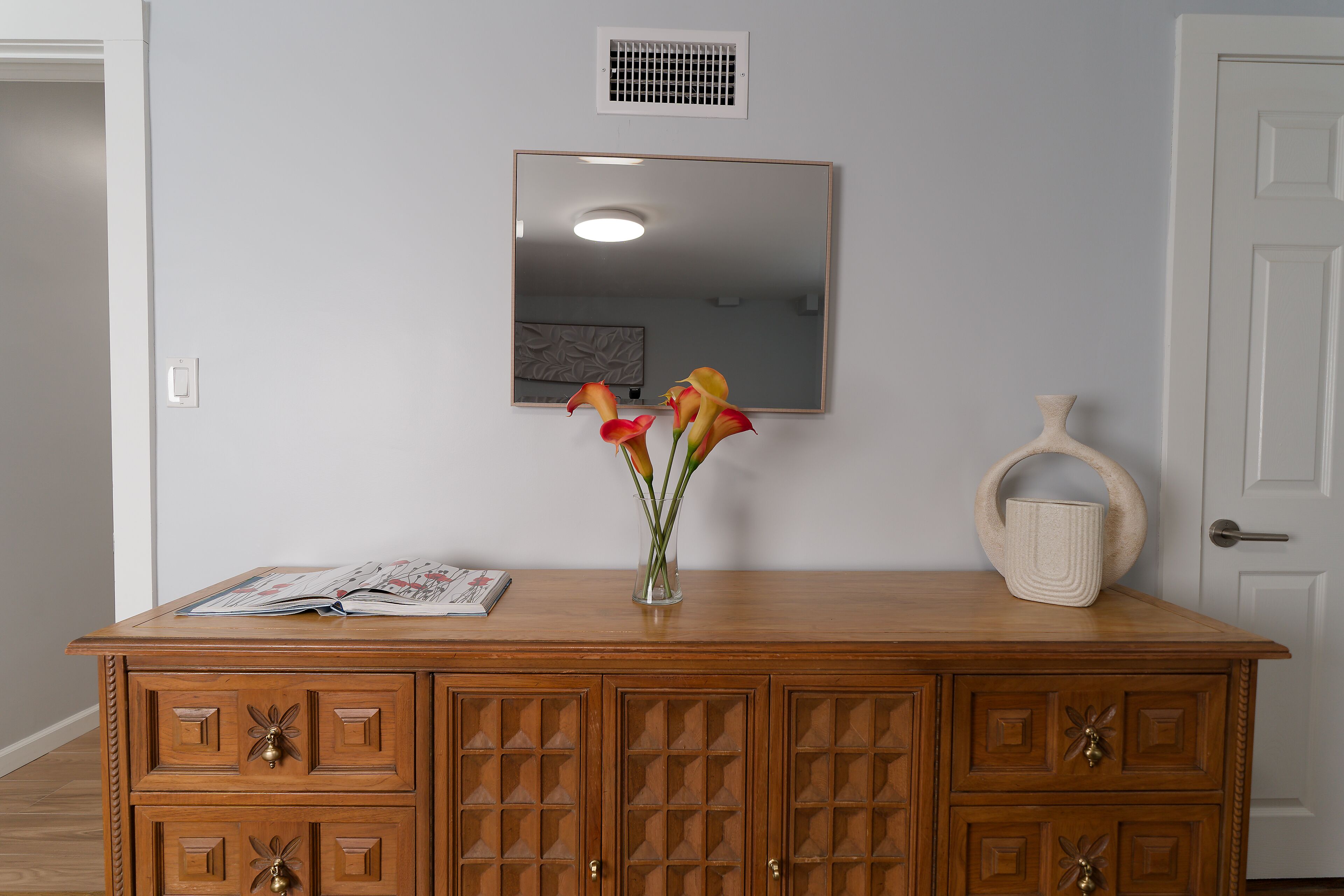 Un mueble de madera con cajones y un florero encima.