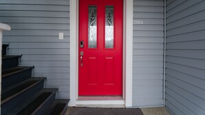 A red door with a white frame, a number '206A' on the wall, and a set of stairs leading up to it.