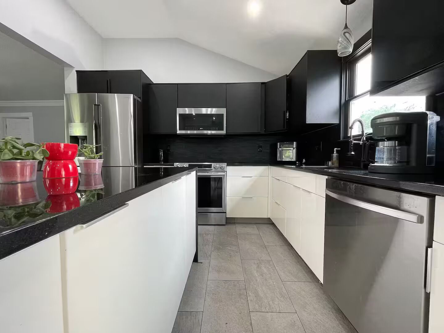 A modern kitchen with black cabinets, stainless steel appliances, and a central island.