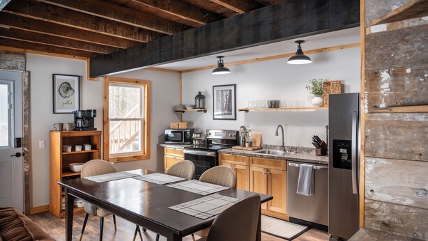 Une cuisine moderne avec des meubles en bois, une table à manger avec des chaises et un réfrigérateur.