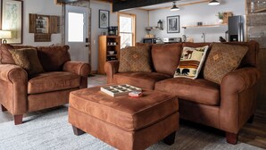 Un salon chaleureux avec deux canapés en cuir marron, un pouf assorti et une table basse en bois.