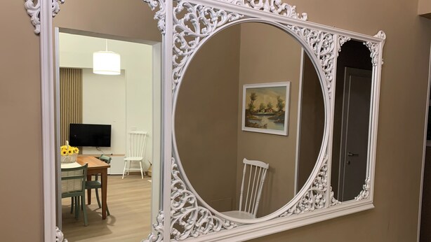 A large ornate mirror with intricate designs on a beige wall.