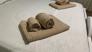 A bed with two rolled towels and a nightstand with a lamp.