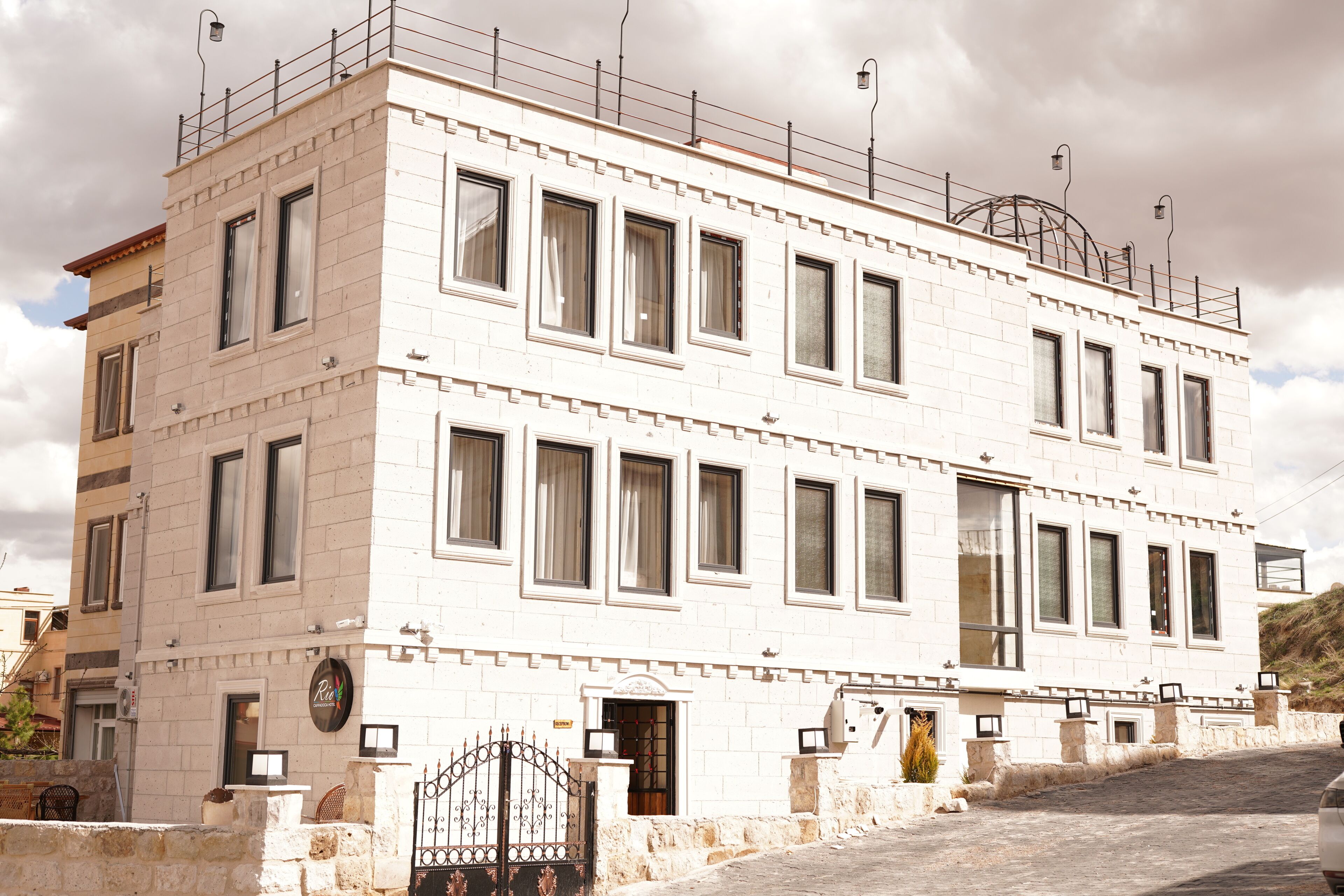 A multi-story building with a white facade, multiple windows, and a gated entrance.