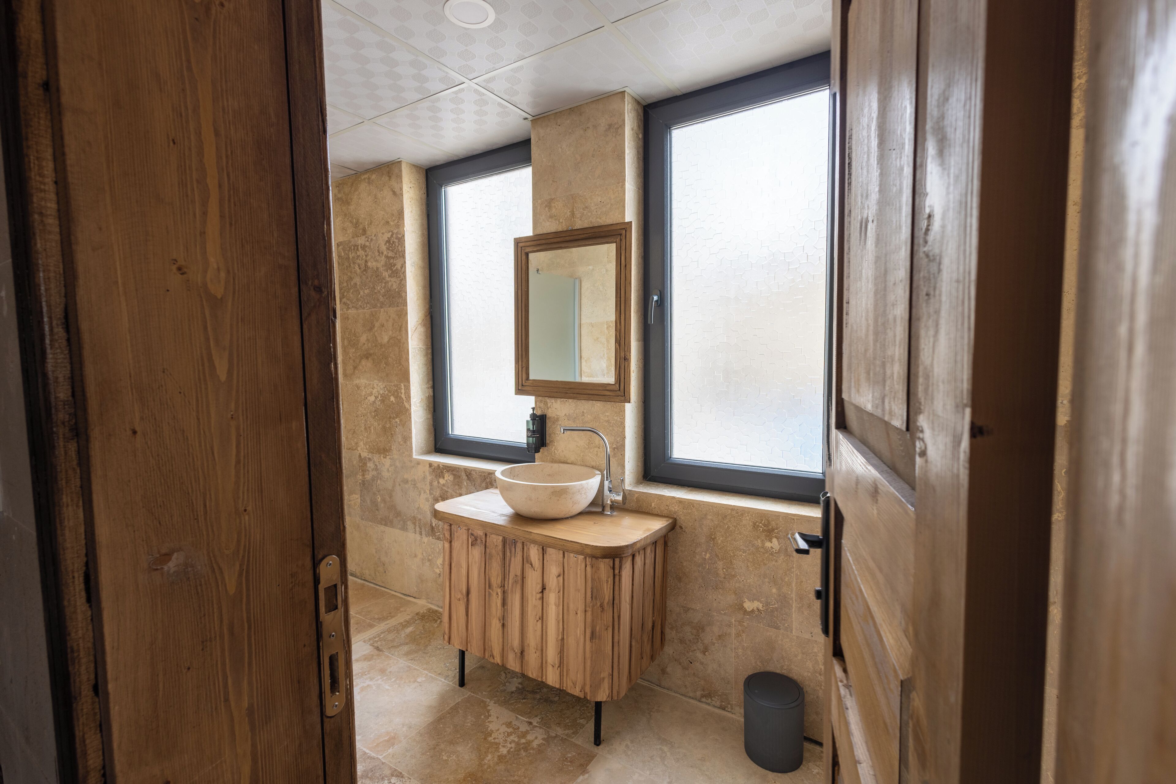 Un baño con tocador de madera, un ventanal grande y un espejo.