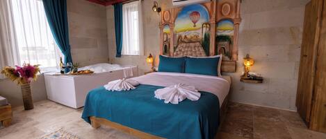 A bedroom with a bed, a nightstand, a lamp, a vase with flowers, and a wall mural.