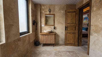 A bathroom with a wooden vanity, a large mirror, and a window.