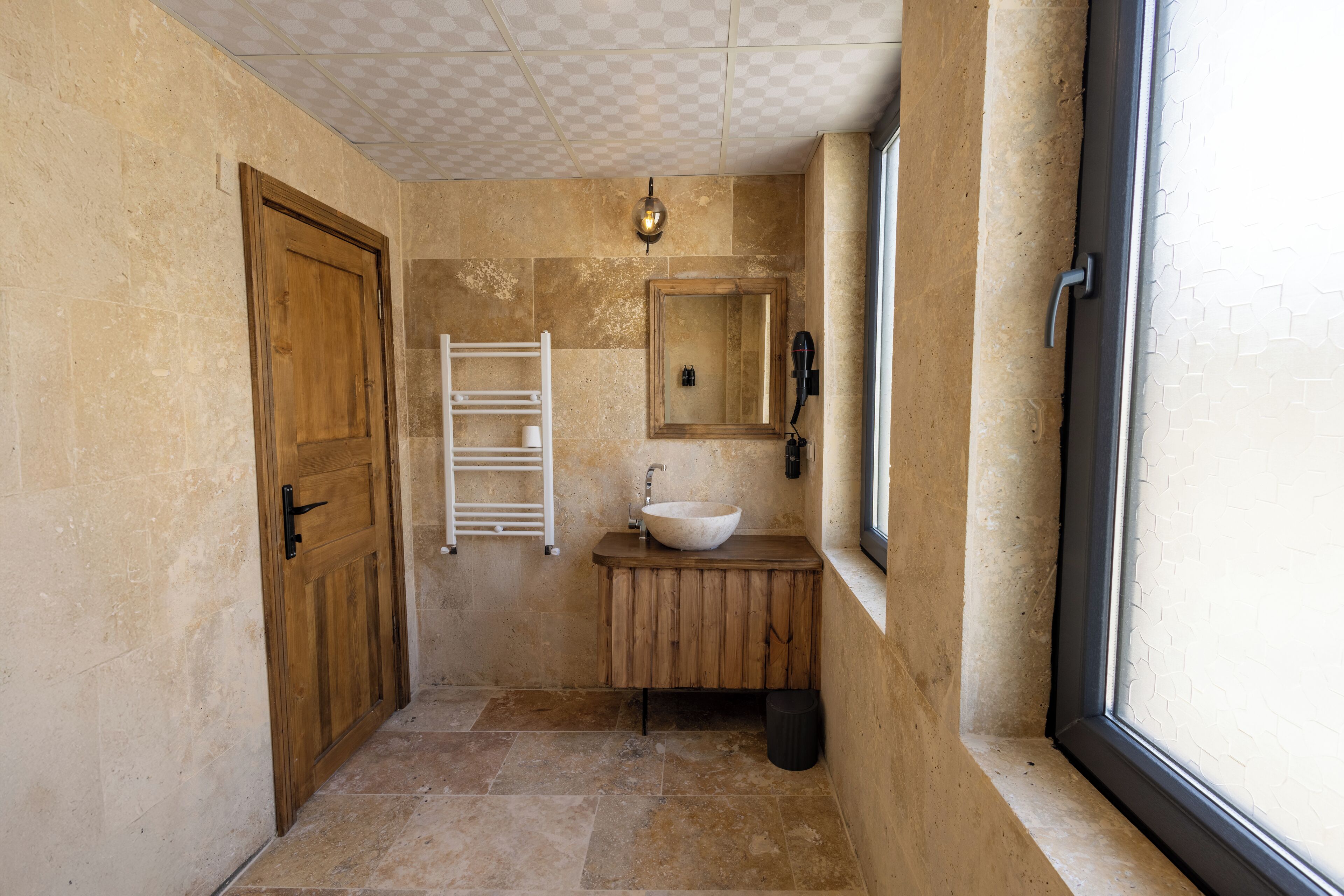 A bathroom with a wooden door, a white sink, a towel rack, and a mirror.