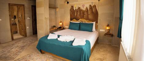 A bedroom with a bed, two bedside lamps, a headboard with a mountain design, and a large window with curtains.