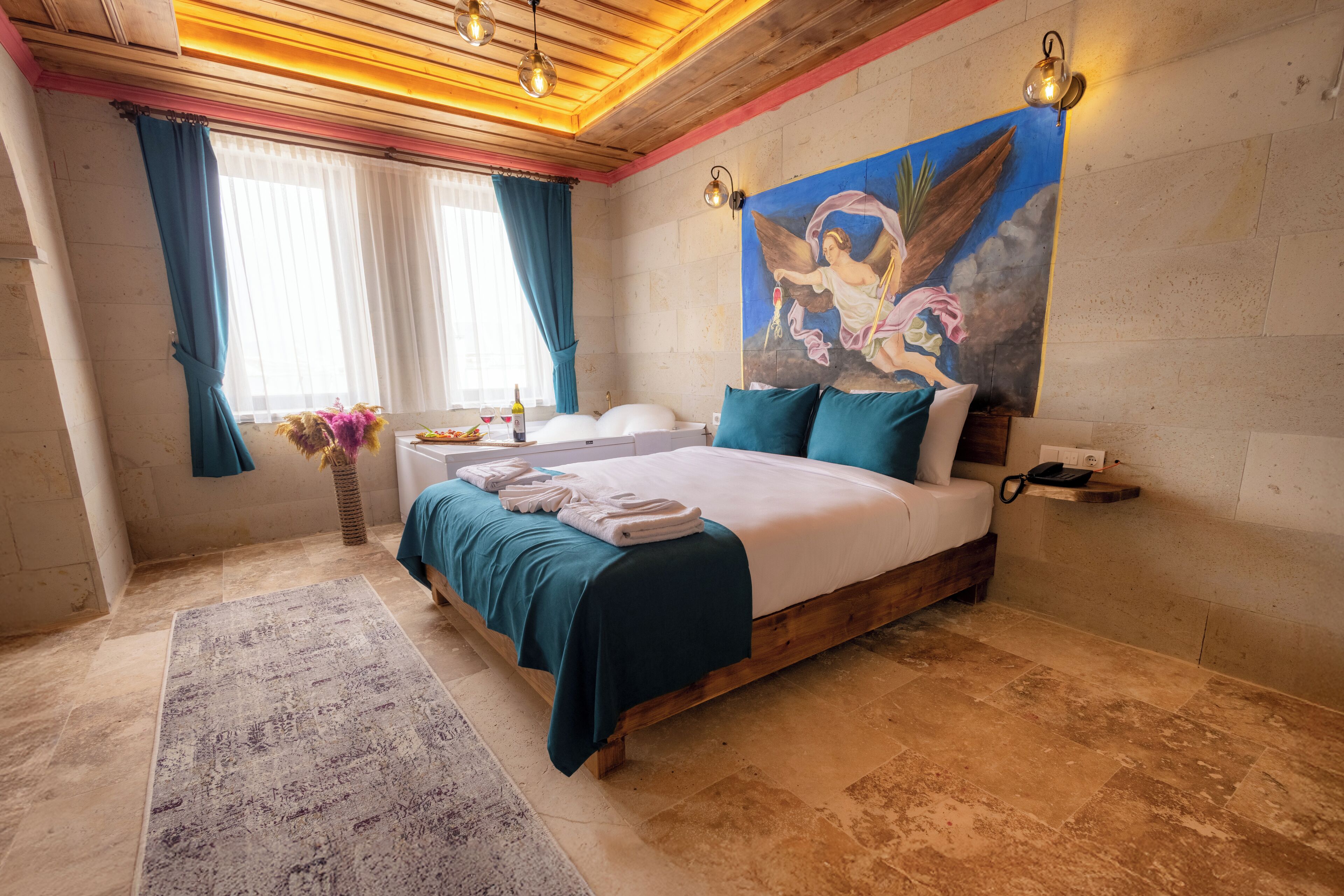A spacious bedroom with a large bed, a wooden headboard, a painting on the wall, and a view of the city.