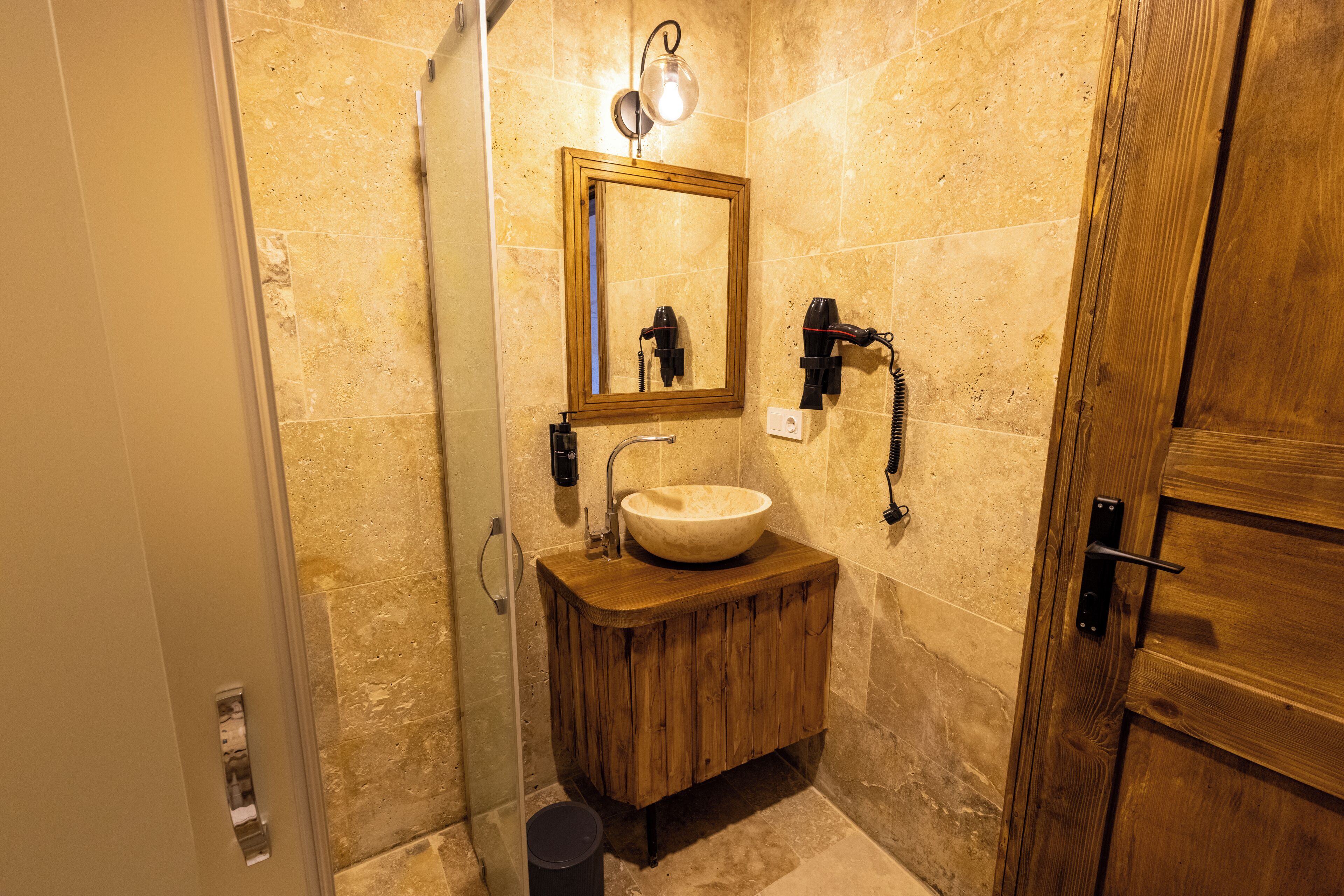 A bathroom with a wooden vanity, a round sink, a mirror, and a towel rack.